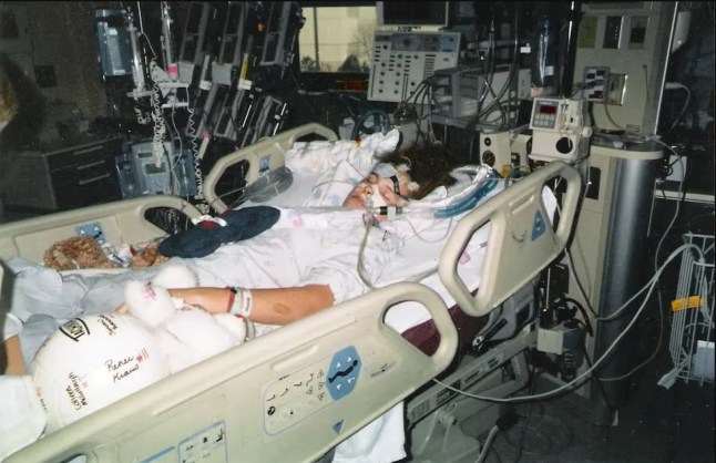 Jeanna Giese laying on a hospital bed hooked up to multiple machines.