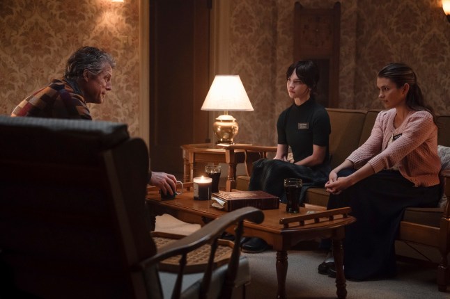 This image released by A24 shows Hugh Grant, from left, Sophie Thatcher and Chloe East in a scene from 
