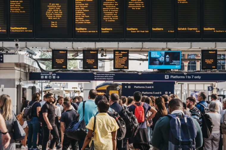 London, UK - July 16, 2019: People waiting for the platform announcement inside Victoria train station, one of the busiest railway stations in London, UK. Selective focus, motion blur.