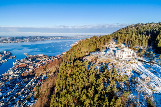 A sunny view from Mount Ulriken, the highest mountain in Bergen, Norway, over blue sea and buildings.