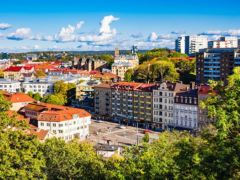 A cityscape in Gothenburg, Sweden featuring numerous tall buildings towering above a lush green landscape of trees.