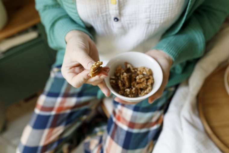 Woman holding bowl of nuts at home