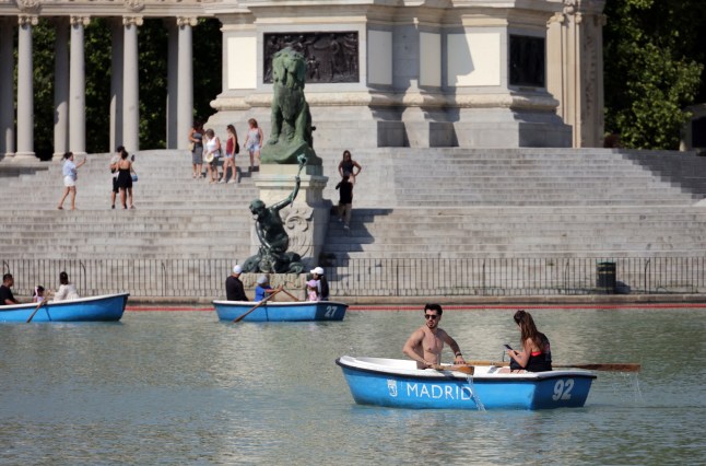 People sail on a lake in a park during the first heatwave of the summer in Madrid