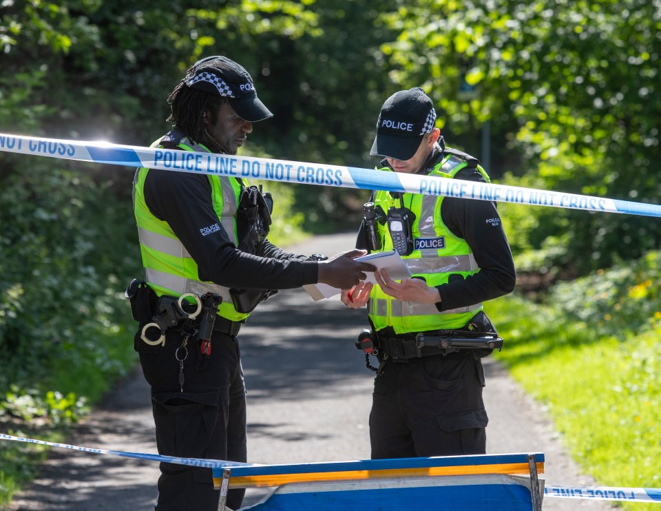 Two police officers reviewing documents at a crime scene.
