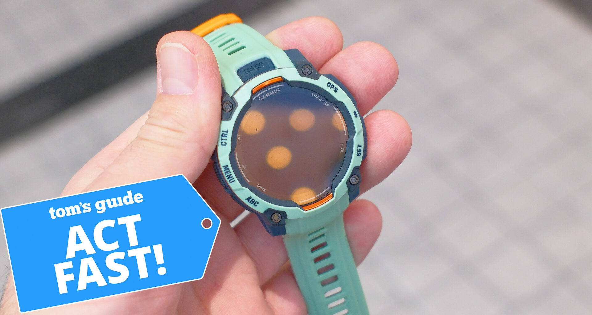 Garmin Instinct 3 in teal in a user's hand next to a deals badge