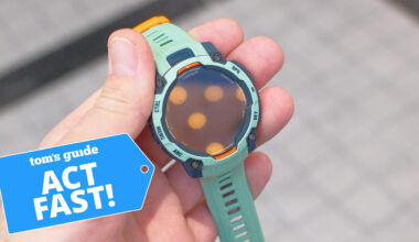 Garmin Instinct 3 in teal in a user's hand next to a deals badge