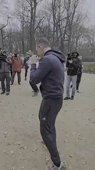 Man shadow boxing surrounded by people with cameras.