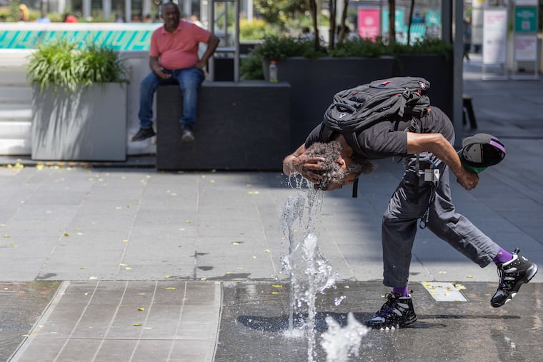 Hasan Grant uses a water jet at Dilworth Park to stay cool Wednesday during Philadelphia's heat wave.