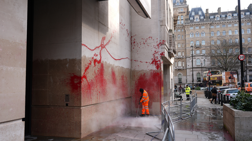 A cleaner pressure-washes red paint sprayed on the side of the BBC's Broadcasting House in London