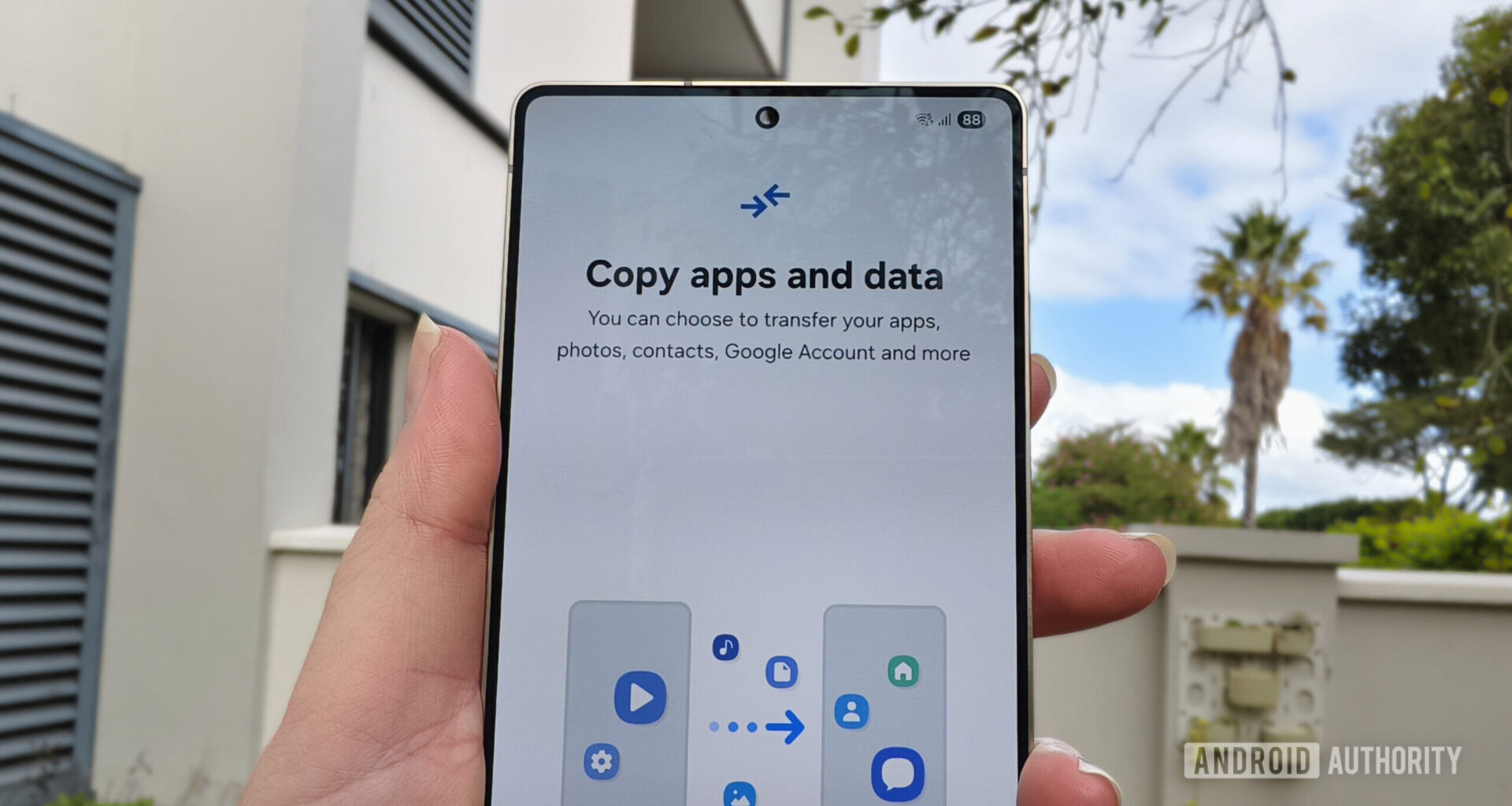 a smartphone held in a hand with a prompt to copy apps and data