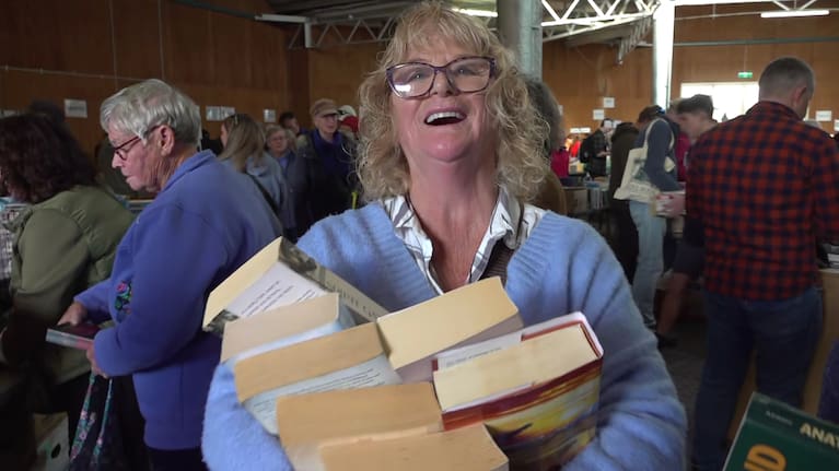 A woman proudly shows off her haul from the Founders Book Fair.