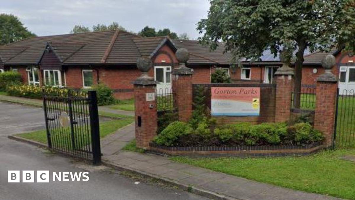 A sign for Gorton Parks Care Home hangs on a wall at the entrance to the nursing home complex. Red brick bungalows can be seen behind.