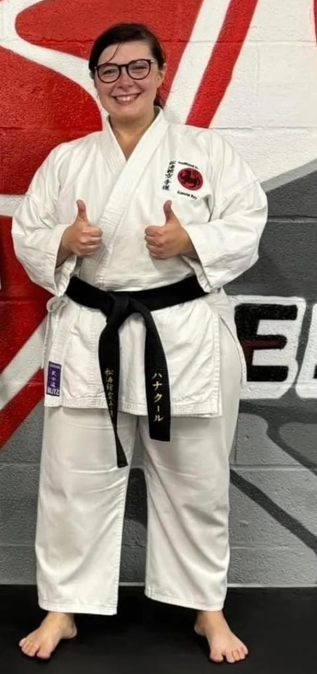 Woman in karate uniform giving thumbs up.