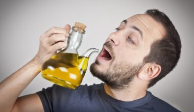 Man holding a jug of olive oil and pretending to drink from the spout