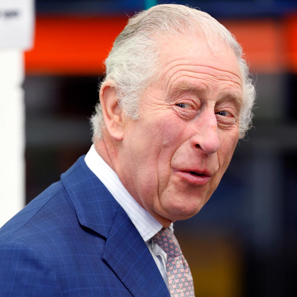 King Charles laughs while wearing a navy suit. 