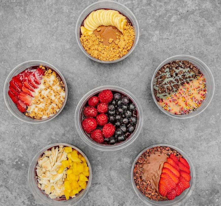 Six acai bowls with various toppings.