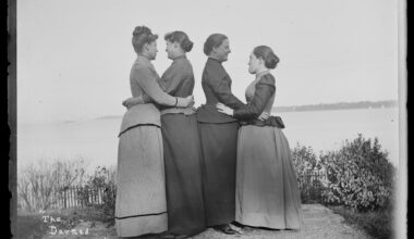 a black-and-white photo from the late 19th century of four women, turned to each other in twos and embracing