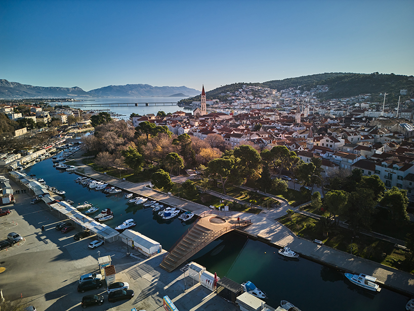 slender steel bridge with integrated net seating expands over foša port in croatia