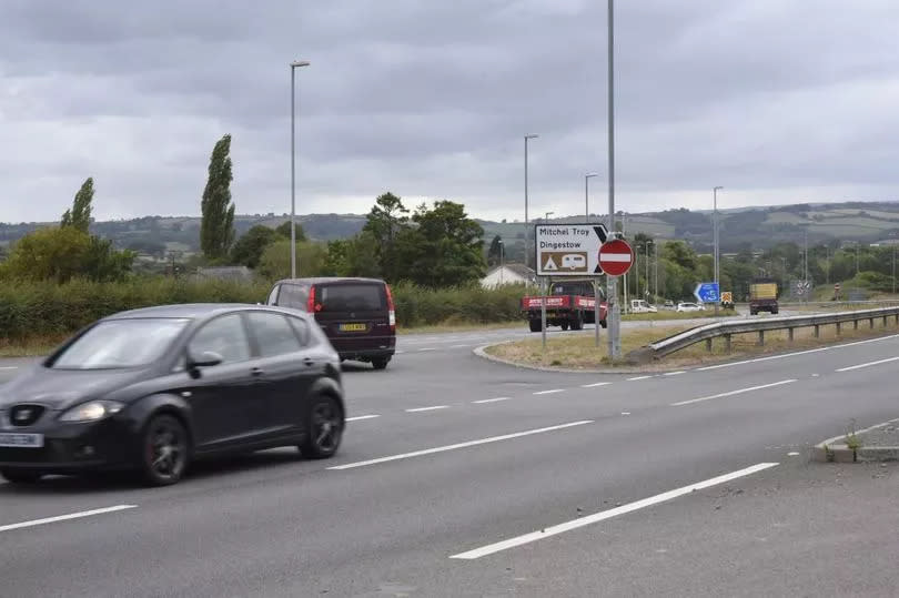 The image shows a car waiting in the central reservation