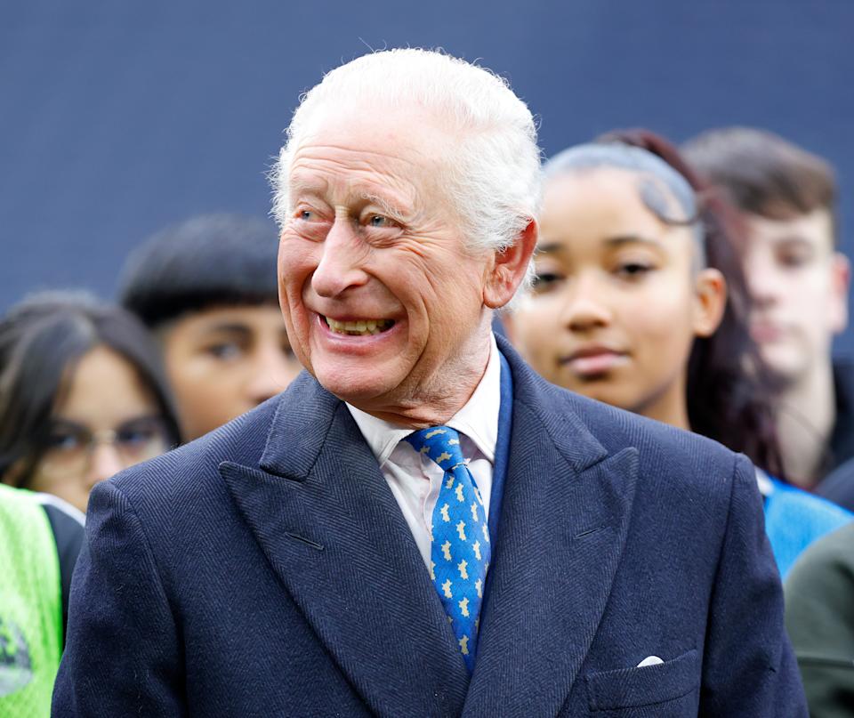 King Charles smiling in a blue coat and tie