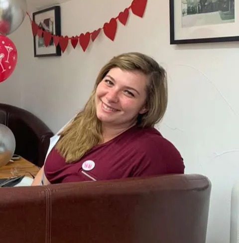 Woman smiling in a maroon shirt.