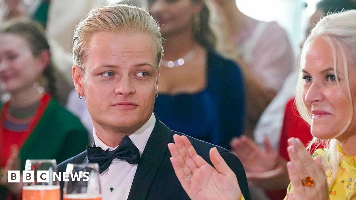 Marius Borg Høiby sitting next to his mother Norwegian Crown Princess Mette-Marit. He is wearing a black suit with a bow tie and his mother is wearing a yellow dress. Both have blonde hair.