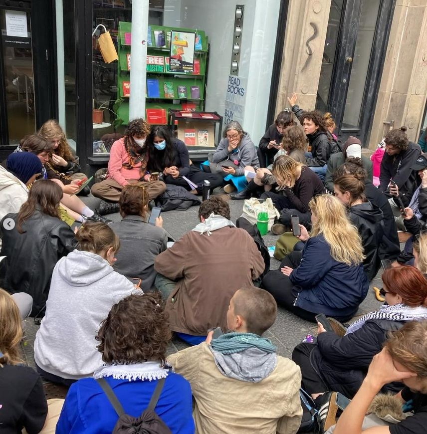 Group of people sitting on the ground looking at their phones.