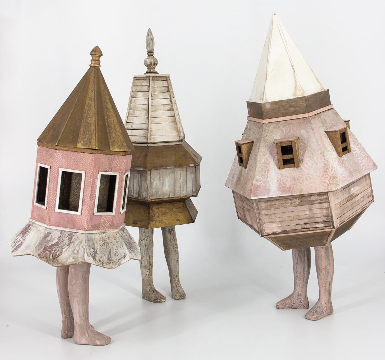 a group of three small sculptures of a small buildings with two legs