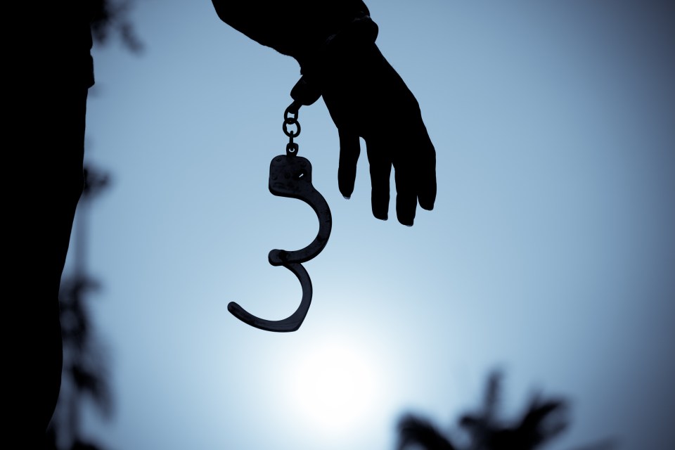 Silhouette of a person's hand removing handcuffs.