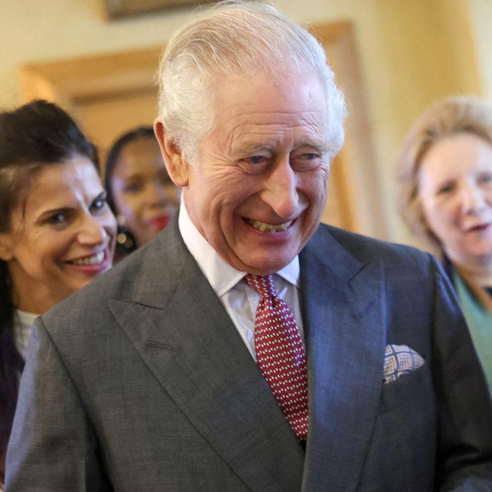  King Charles wearing a gray suit and laughing. 