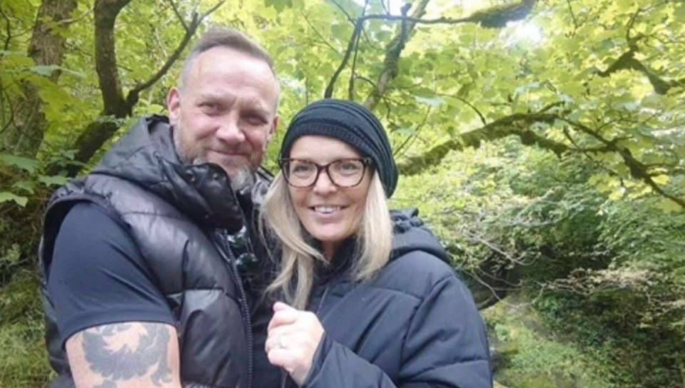 Photo of a couple embracing in a wooded area.
