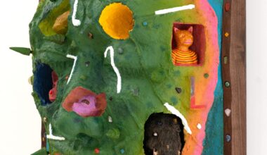 a side view of a wooly mammoth, pink animal, bell, and other objects embedded into a sculptural painting shaped like a face