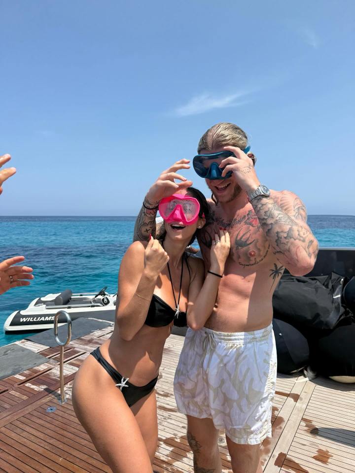 A man and woman in swimsuits holding snorkeling masks on a boat.