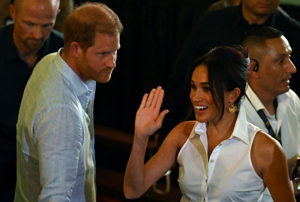 Prince Harry and Meghan Markle waving to attendees at a forum in Cali, Colombia.