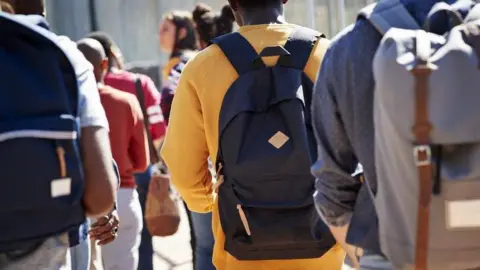 Getty Images The backs of a group of students carrying backpacks. They are unidentifiable.