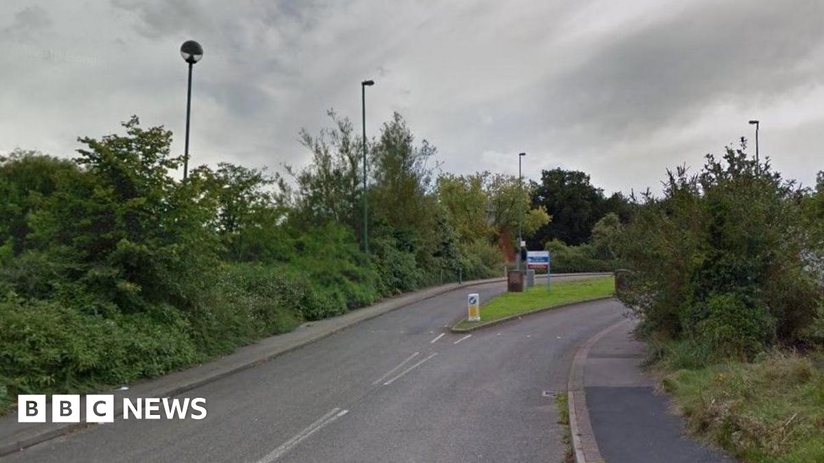 A road leading up to the entrance of the Reaside Clinic. There is a blue and white sign identifying the site.