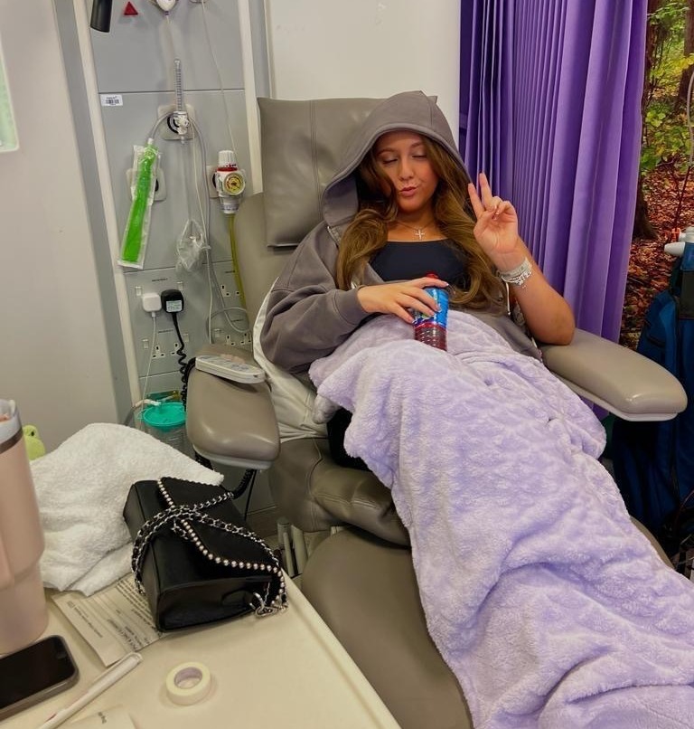 Young woman in hospital chair receiving treatment.