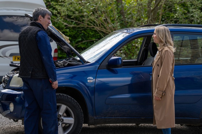 Belle talking to Cain next to a car in Emmerdale