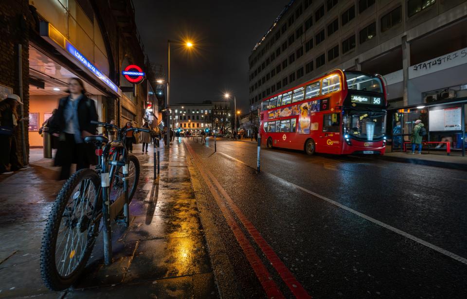 Nighttime view of London Bridge Underground Station entrance with a bus and bicycle.