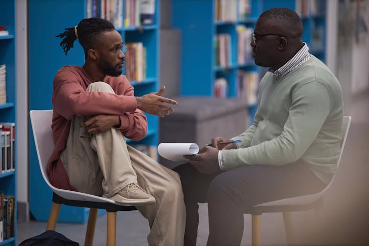 A student and mental health therapist sit and talk in a college library