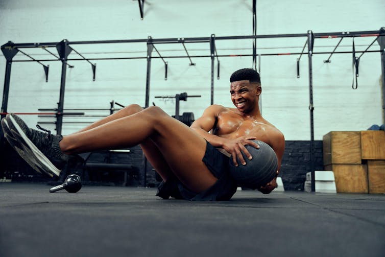 A young man doing an intense workout with a medicine ball.