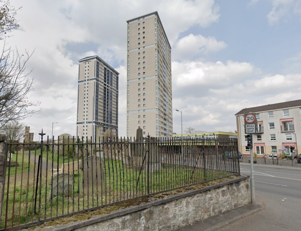 Two high-rise apartment buildings behind a cemetery fence.