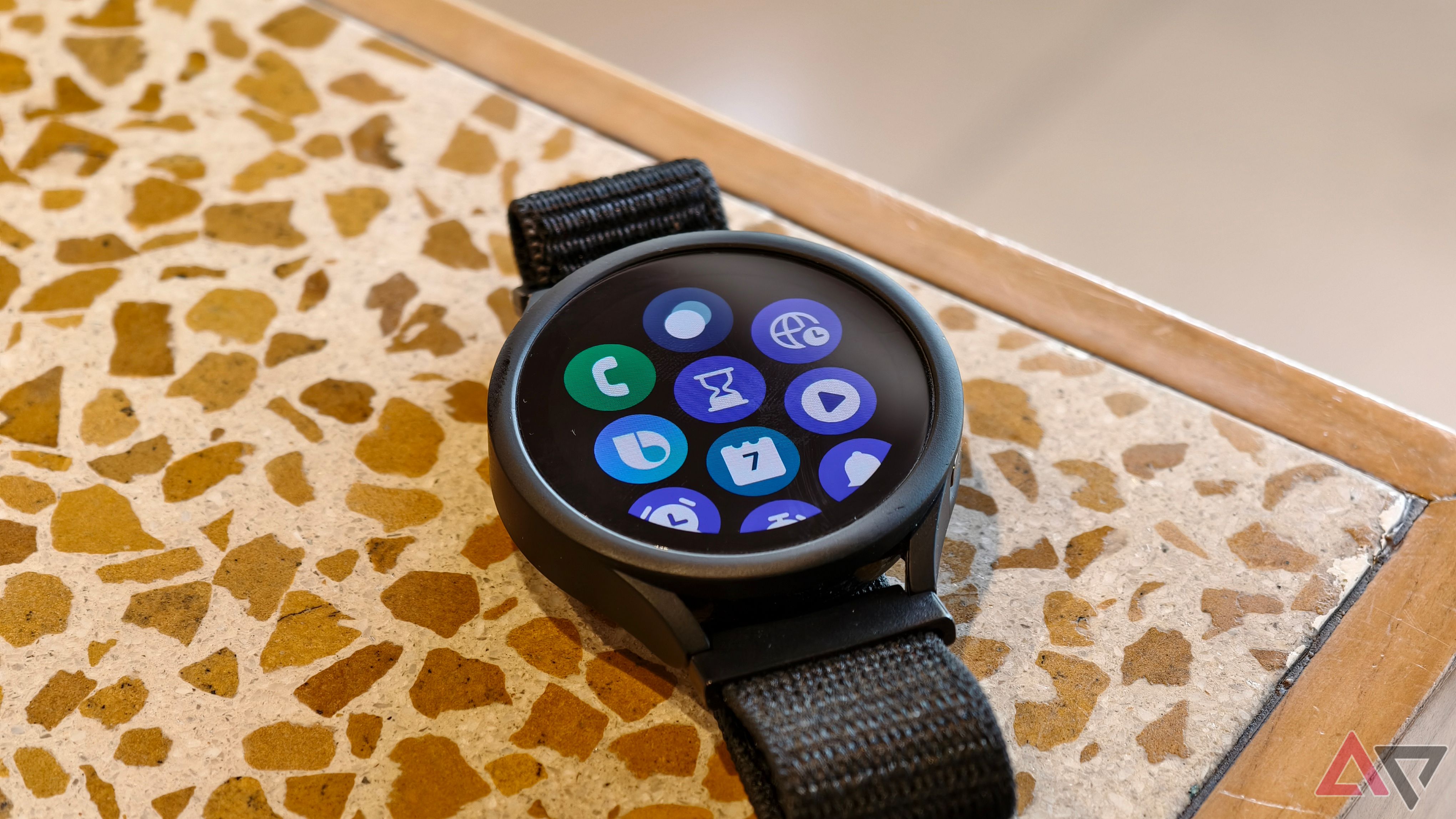 Galaxy Watch 4 kept on a table showing a collection of apps on the screen