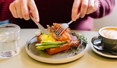 A man&apos;s hands cutting a salmon and avocado flatbread with a knife and fork.