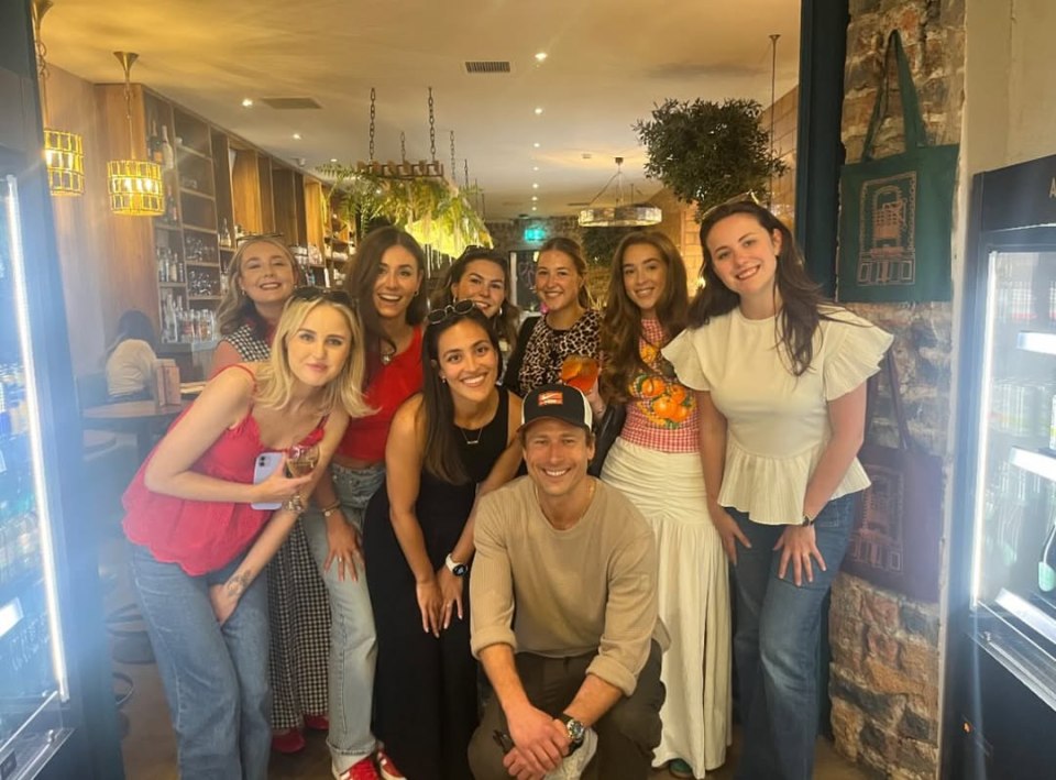 Glen Powell with a group of women at a restaurant.