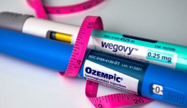 Ozempic and Wegovy pens wrapped in a pink tape measure on white background