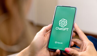 Woman using a mobile phone with ChatGPT on the screen.