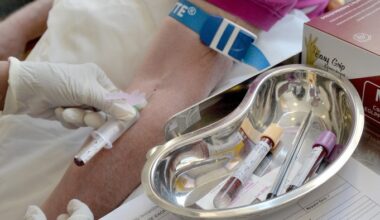 A nurse takes blood from a patient’s arm