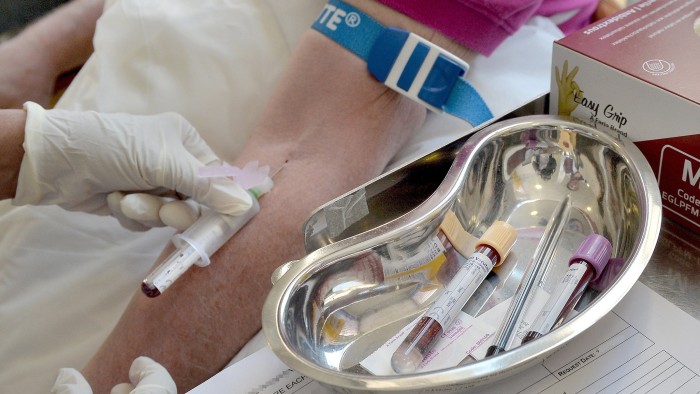 A nurse takes blood from a patient’s arm