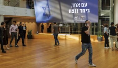 An electronic ticker displays stock price information above a sign reading ‘One Nation, Together We Will Win’ in the foyer of the Tel Aviv Stock Exchange